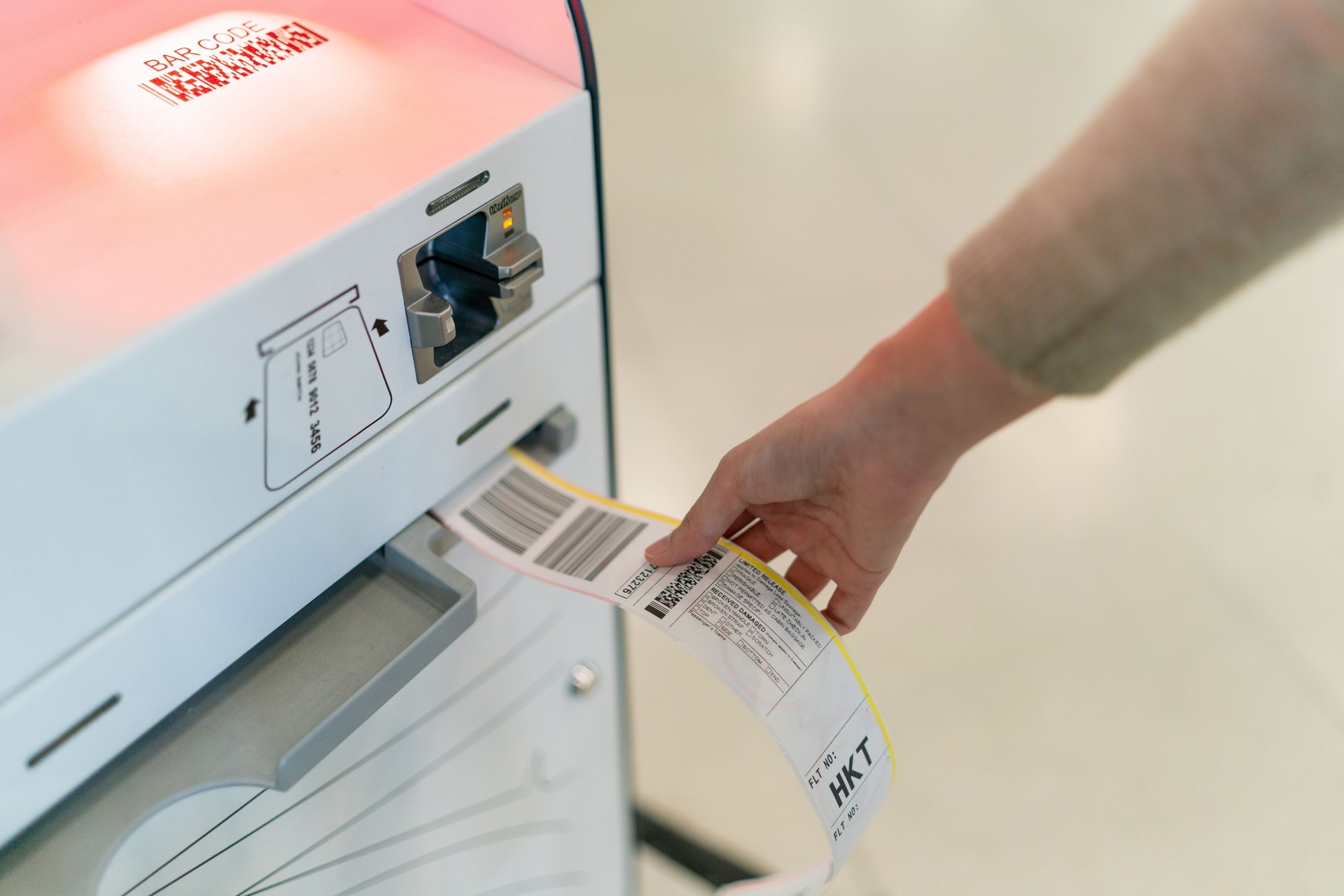 Close up of self check-in baggage tag printed. Young Asian Woman checking in at the airport using an automated self service check-in kiosk. Ready to travel.